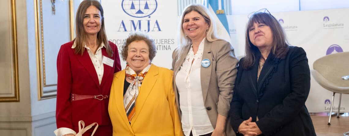 Camila Banfi posan frente al cartel de AMJA en la Legislatura de la Ciudad de Buenos Aires.